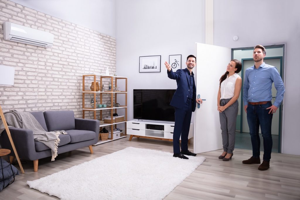 Male Agent Showing Couple Staged Living Room